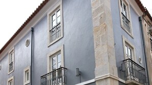 Un edificio de varios pisos con balcones, ventanas amplias y base de piedra.