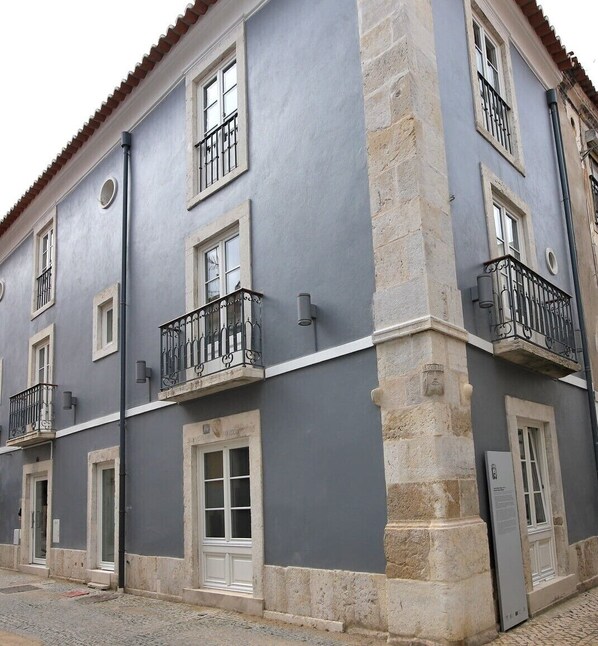 A multi-story building with balconies, large windows, and a stone base.