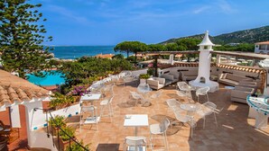 Eine Terrasse mit Sitzgelegenheiten im Freien, einem Pool und Blick aufs Meer.