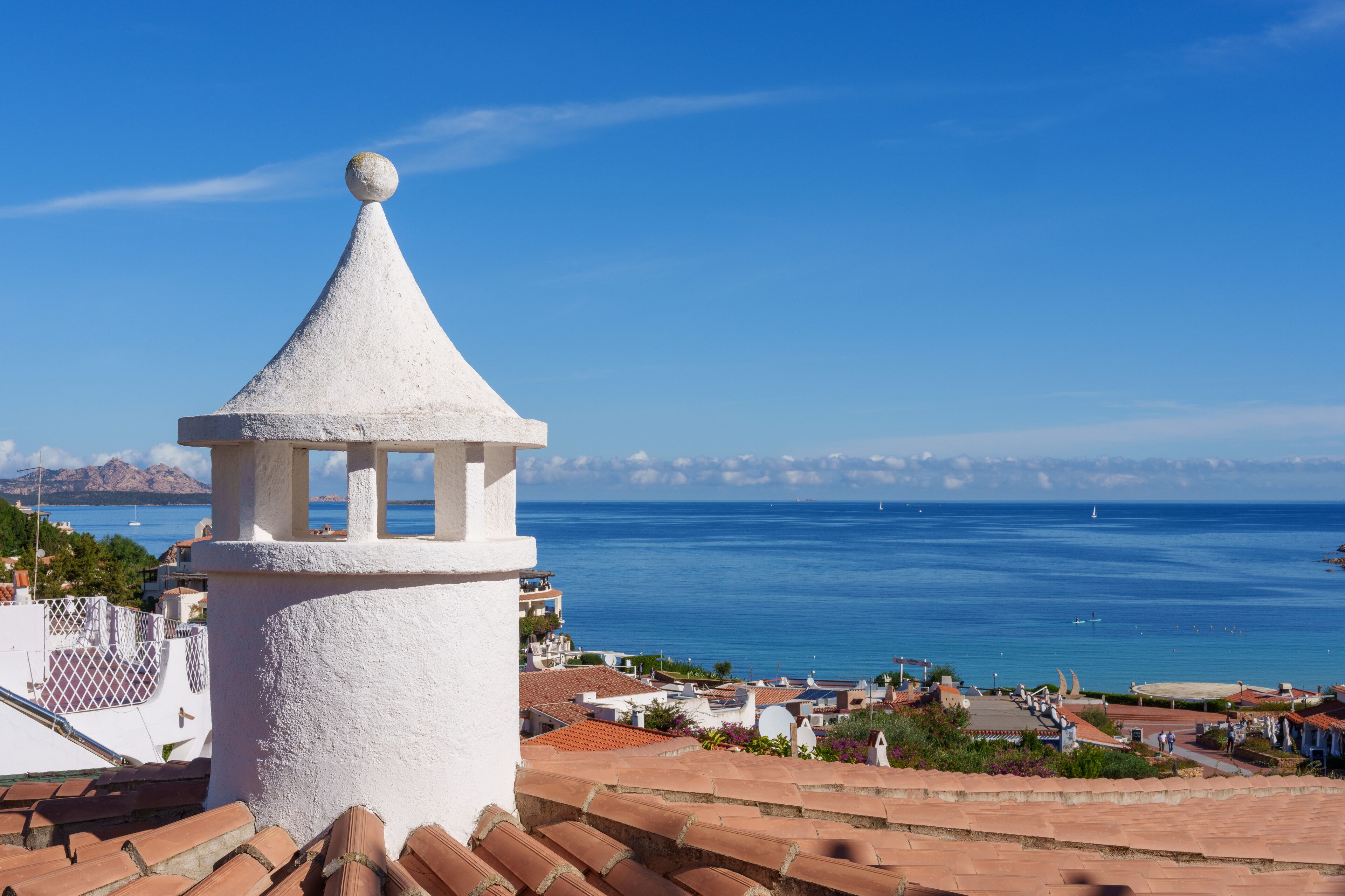 A coastal view with a white tower and terracotta roofs.