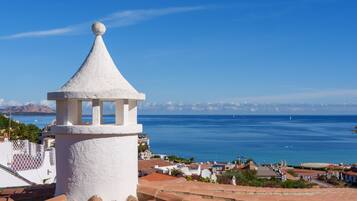 A coastal view with a white tower and terracotta roofs.
