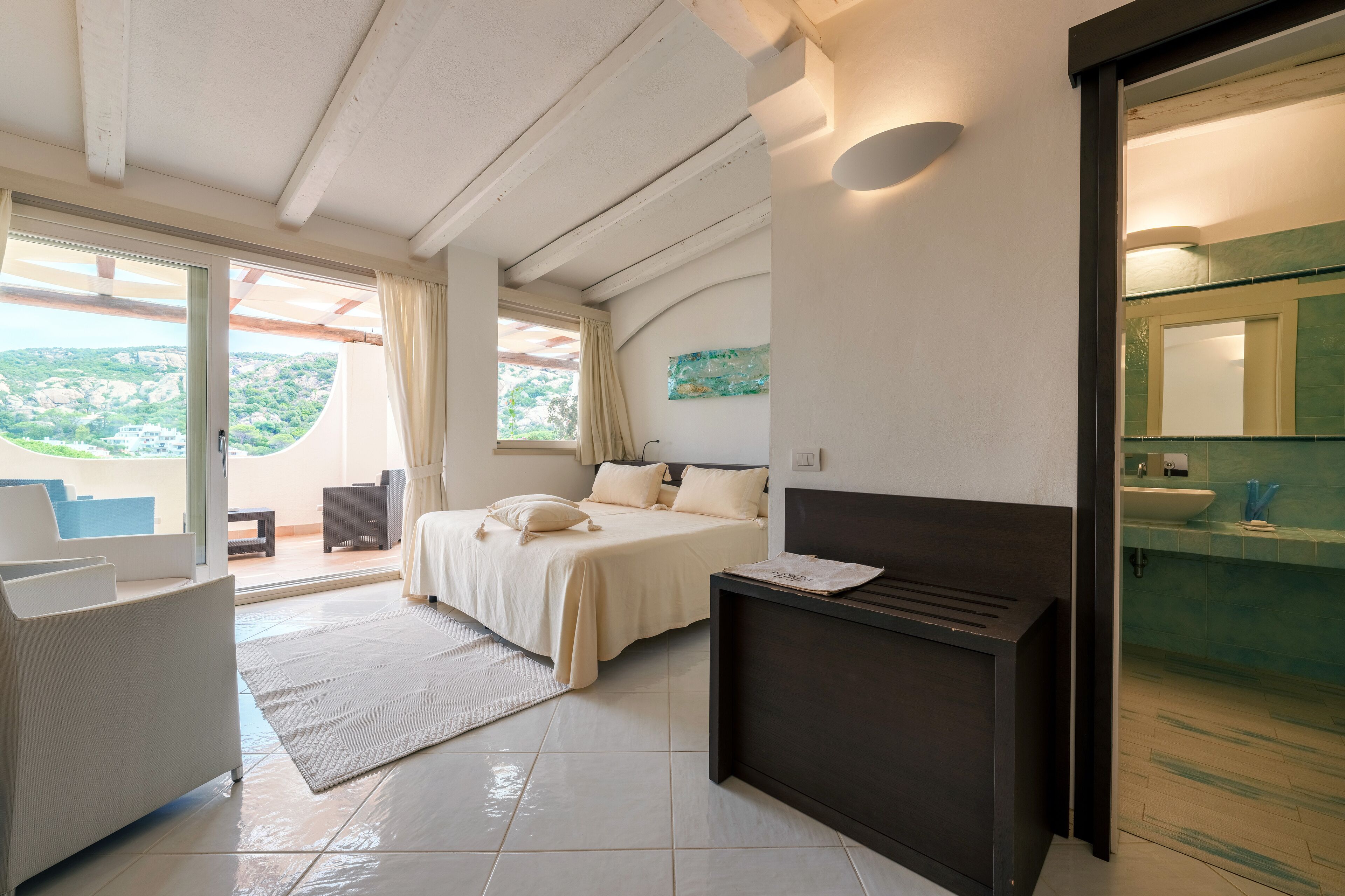 Ein Schlafzimmer mit Bett, Nachttisch und Blick ins Freie.