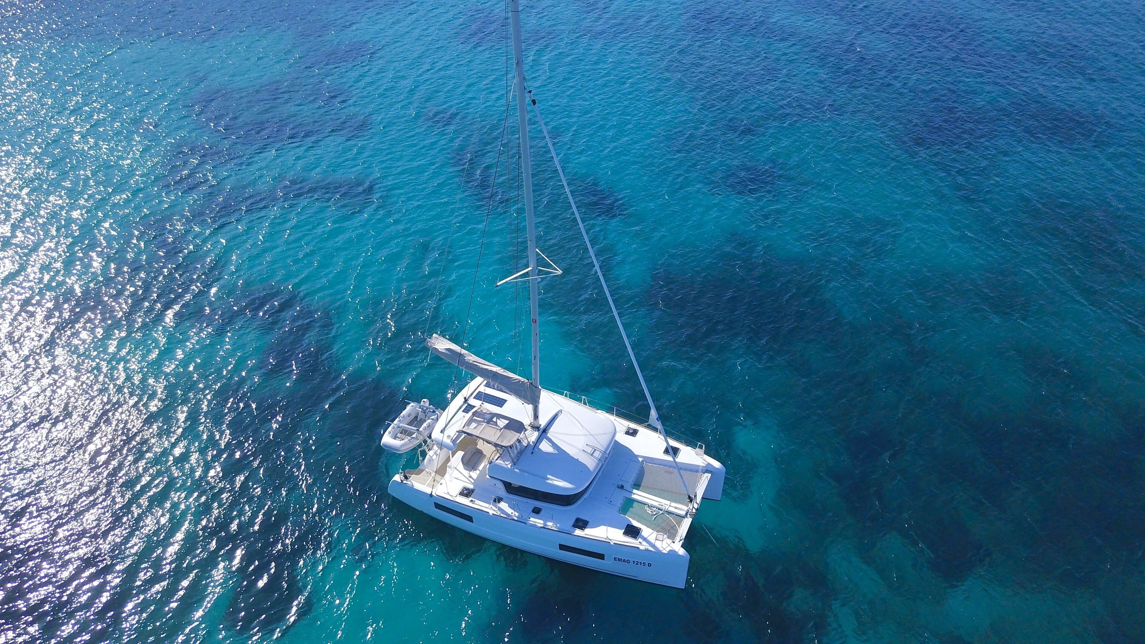 A white yacht anchored in clear blue waters with a cabin and deck area visible.