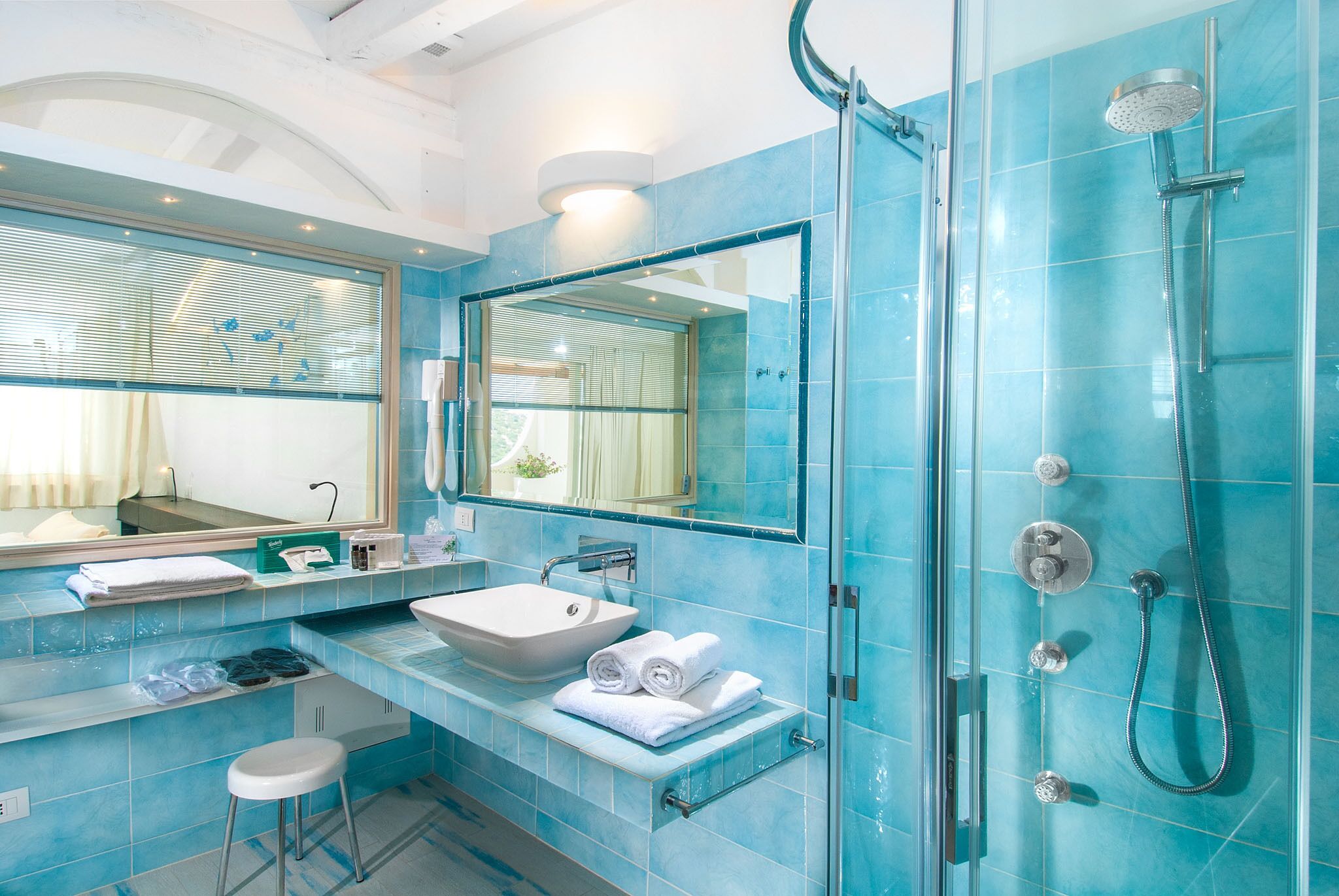 A modern bathroom with a glass shower enclosure, a white sink, and a large mirror.