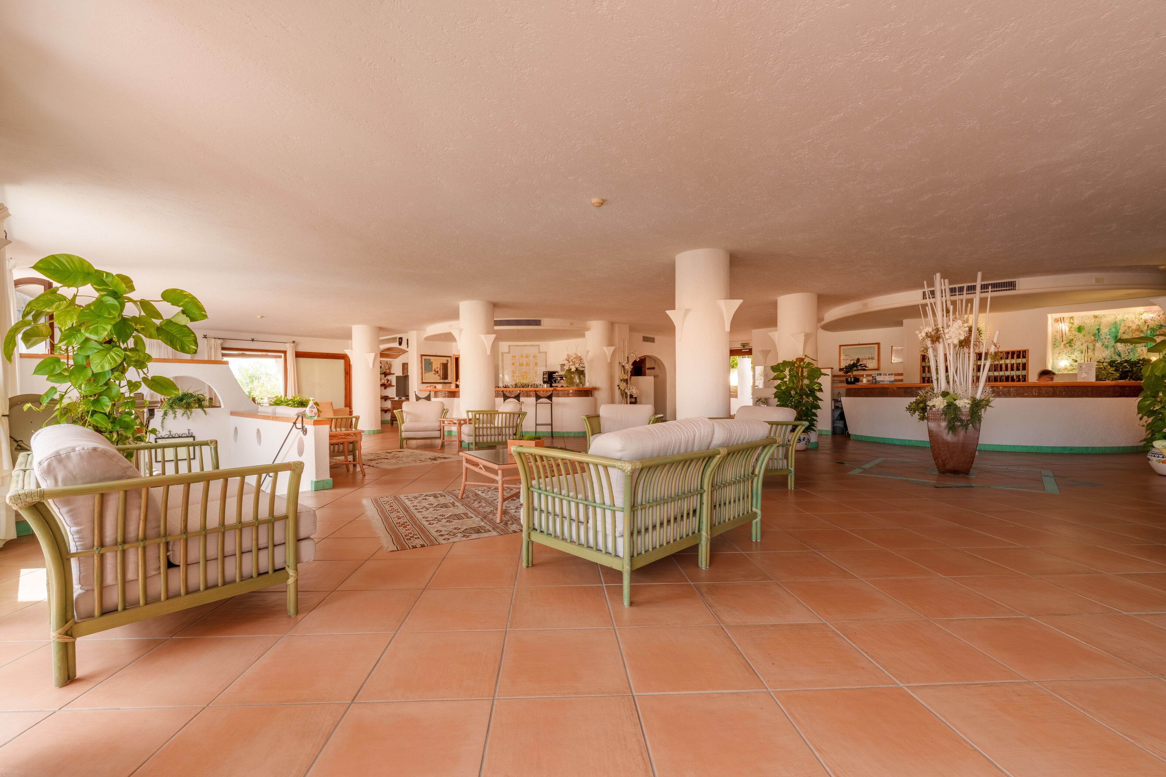 Eine geräumige Lobby mit hohen Decken, großen Fenstern und einer zentralen Sitzecke mit einer Couch und Sesseln.