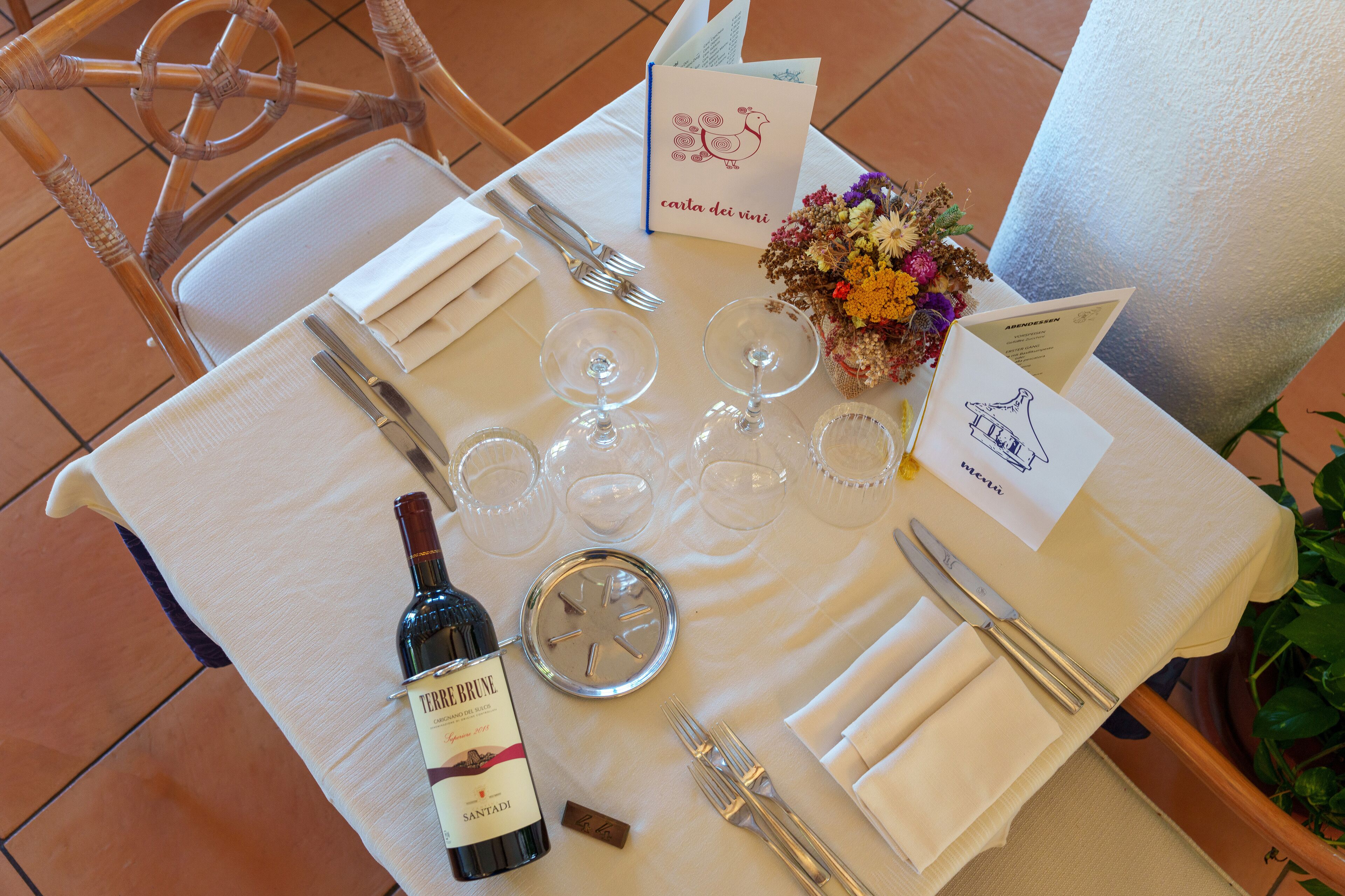 Une table mise pour un repas, avec des verres à vin, des couverts et une bouteille de vin.