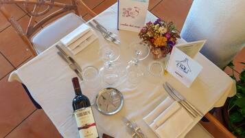 Une table mise pour un repas, avec des verres à vin, des couverts et une bouteille de vin.