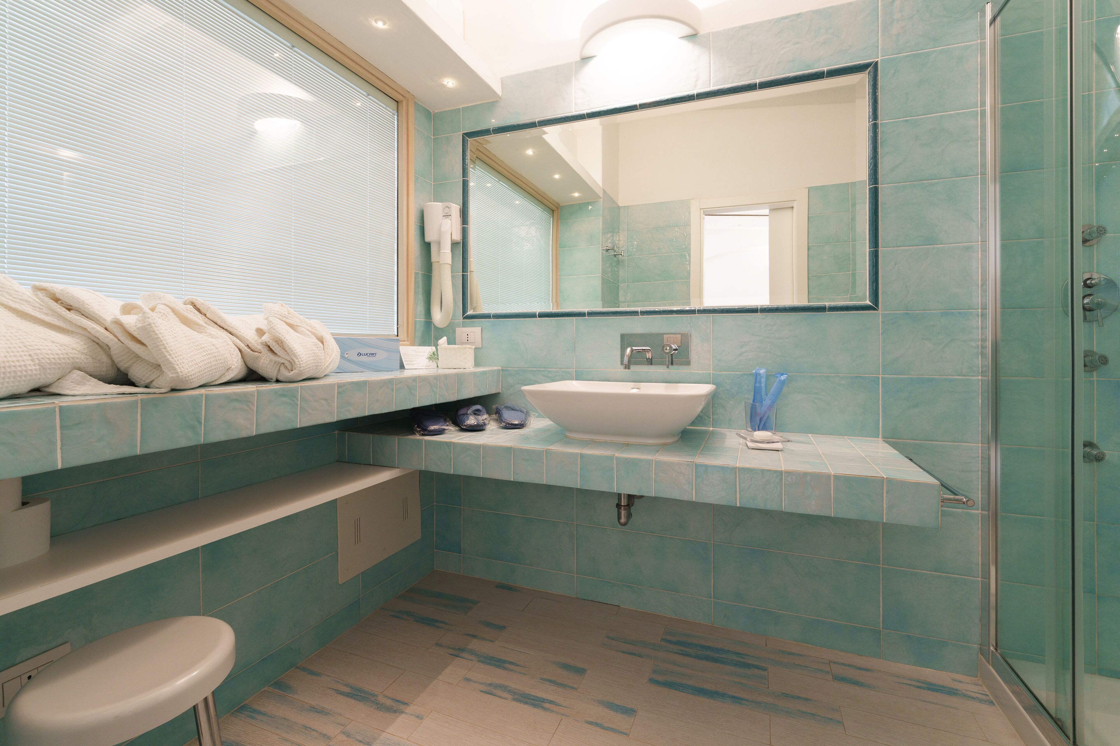 A bathroom with a large mirror, a sink, and a shower area.