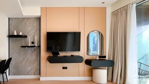 A modern living room with a flat-screen TV, a round mirror, a small table, and a seating area with a chair. - Luxury residence at Fashion Avenue Dubai Mall (Dubai)