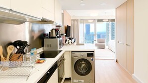 A modern kitchen with a built-in washing machine, a dining area with a view of the city, and a spacious living area with a balcony. - Luxury residence at Fashion Avenue Dubai Mall (Dubai)