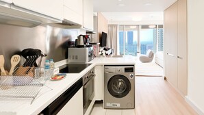 A modern kitchen with a built-in oven, microwave, and dishwasher, leading to a balcony with a city view. - Luxury residence at Fashion Avenue Dubai Mall (Dubai)