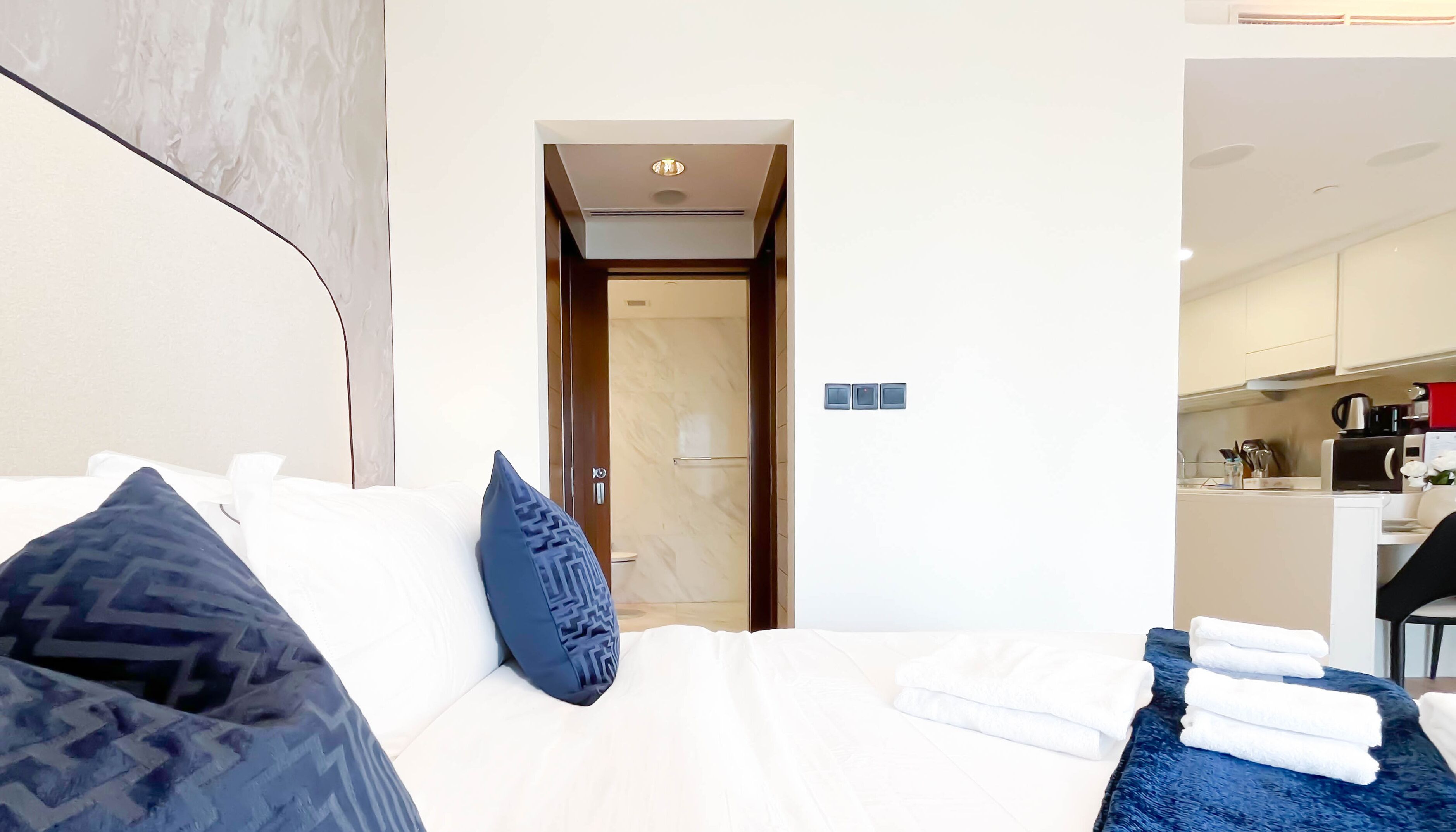A hotel room with a bed, a bathroom, and a kitchenette.