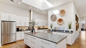 Una cocina moderna con armarios blancos, una isla grande y decoración en la pared.