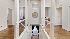 Un interior espacioso con una escalera central, paredes blancas y un adorno en la pared.
