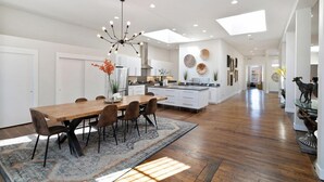 Una cocina amplia con una isla central, iluminación colgante moderna y vista al área de comedor.
