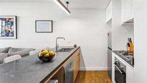 Eine moderne Küche mit integriertem Geschirrspüler, einem Gasherd und einem Essbereich mit einem Marmortisch und einer Obstschale.