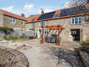 A stone building with a tiled roof, solar panels, a wooden pergola, and a gravel patio. - 3 bedroom accommodation in Pickering (Pickering)