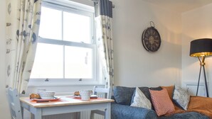 Ein gemütliches Wohnzimmer mit Esstisch, einer Couch und einer Wanduhr.