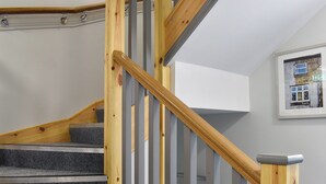 Eine Holztreppe mit grauen Teppichstufen und Metallgeländern.