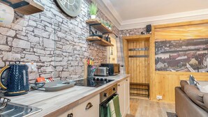 Cocina compacta con pared de piedra, estantes de madera y vista a la ciudad.
