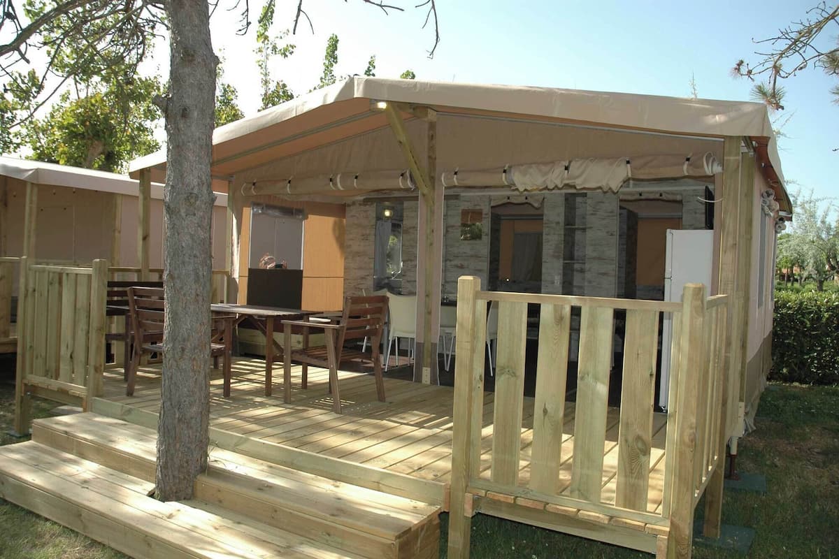 A wooden deck with a covered seating area, a dining table, and chairs.