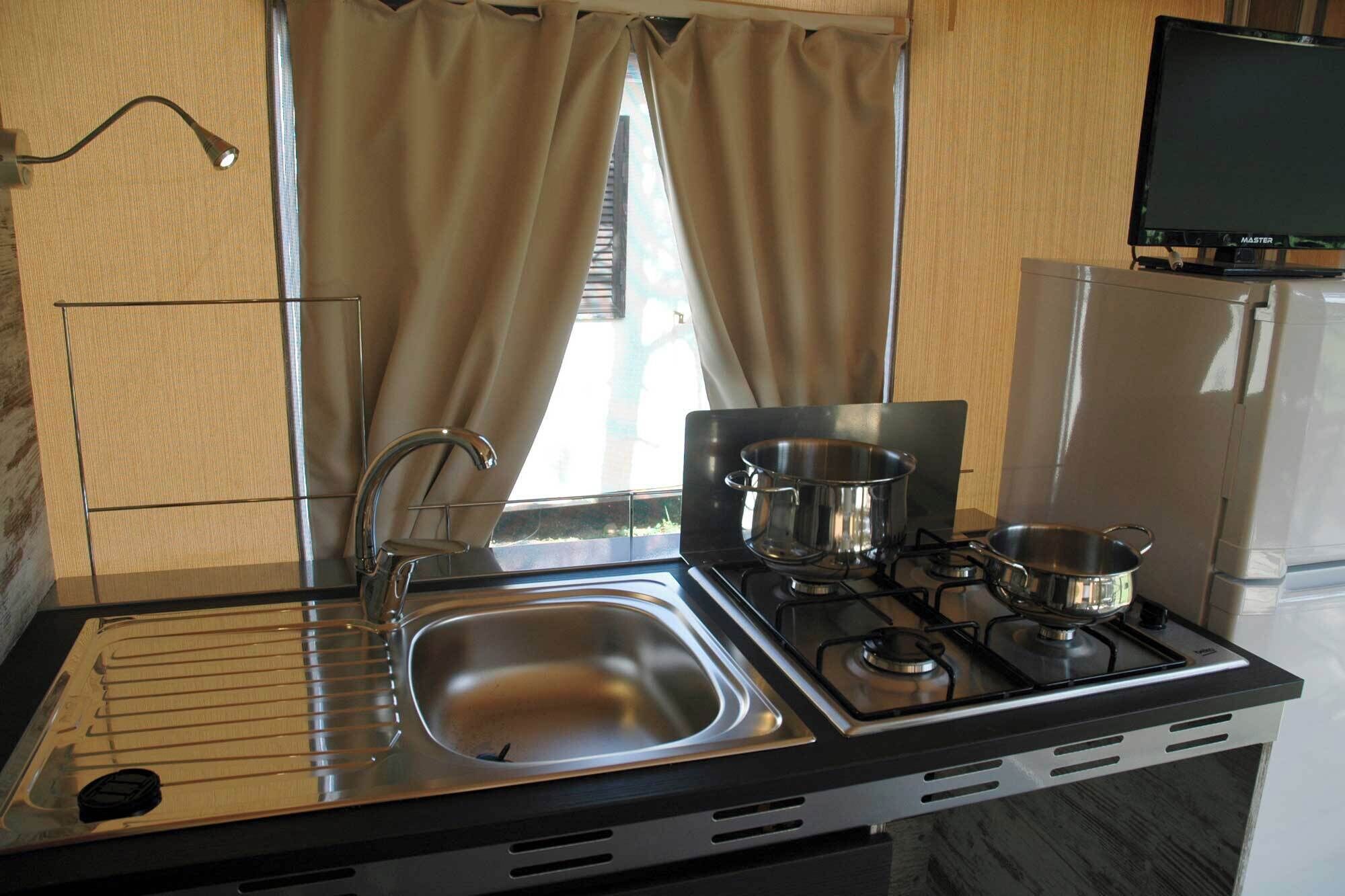 A compact kitchen with a sink, stove, and pots.