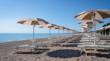 Privatstrand, schwarzer Sandstrand, Liegestühle, Sonnenschirme