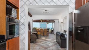 A modern kitchen with a built-in oven, a refrigerator, and a dining area with a view. - Villa Suenios - PlusHolidays (Calpe)