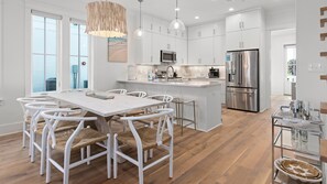 Une cuisine moderne avec des meubles blancs, un îlot central et des appareils électroménagers en acier inoxydable.