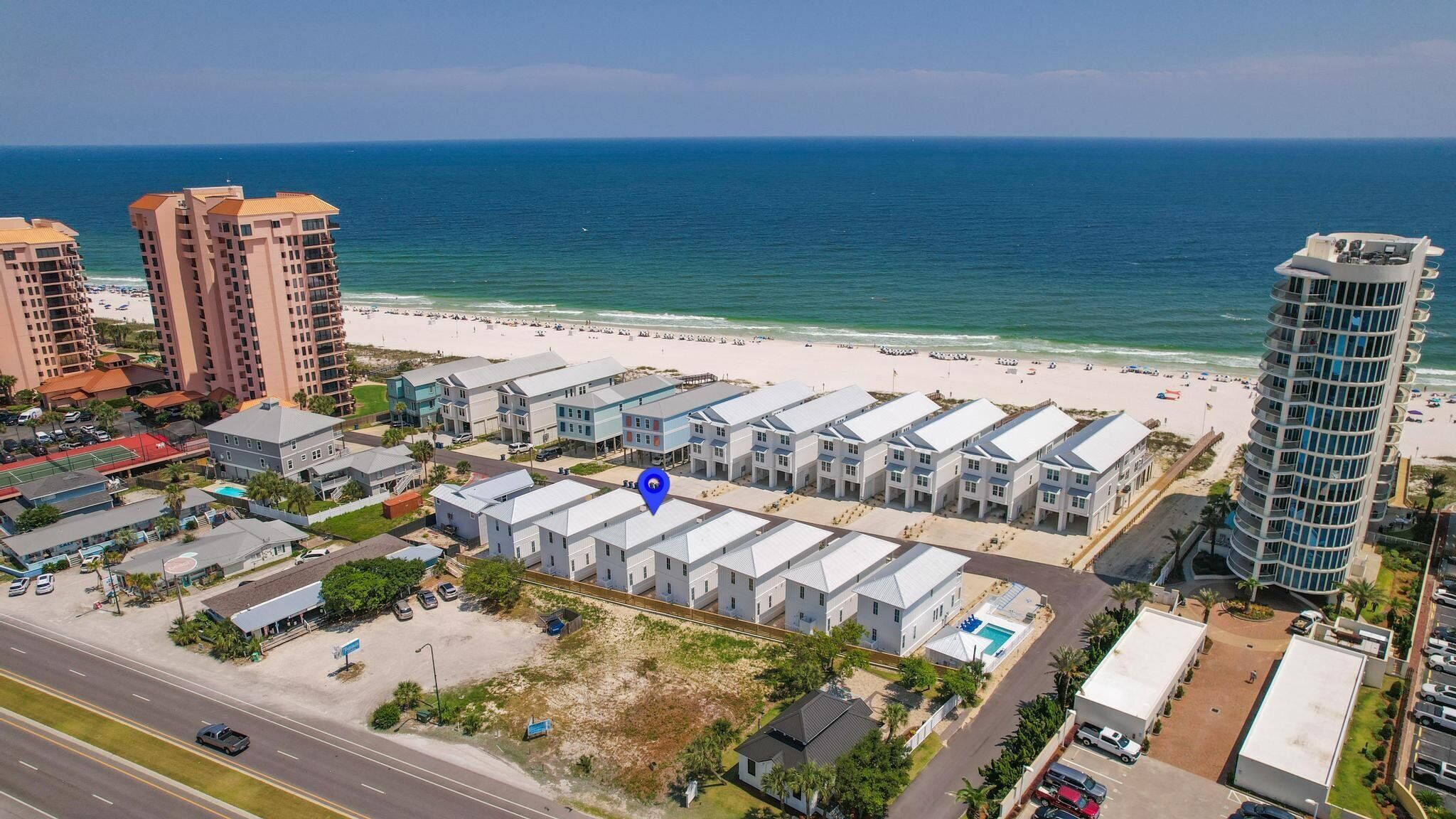 A coastal hotel with multiple-story buildings, a beach view, and a parking area.