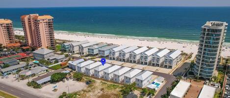 A coastal hotel with multiple-story buildings, a beach view, and a parking area.
