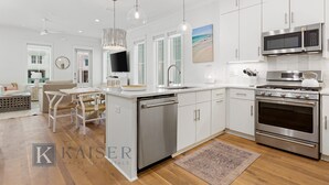 A modern kitchen with stainless steel appliances, a dishwasher, and a large island with seating. - Beach Side Home, Steps from the Sand. Ocean Edge 05 | Bright Side by Kaiser Vacation Rentals. (Orange Beach)
