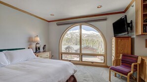 A bedroom with a large window, a bed, a chair, a TV, and a wooden cabinet. - Ski in/Ski Out 100 yards, Masive Views, On Shuttle Route, Hot Tub, Fireplace (Breckenridge)