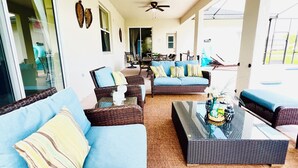 A spacious living area with wicker furniture, a ceiling fan, and a glass coffee table. - By Disney Universal Pvt. Pool Sleeps 10! Game rm Free Bbq, Parking,WiFi, Fishing (Kissimmee)