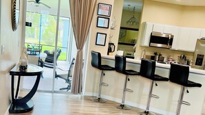 A modern kitchen with white cabinets, stainless steel appliances, and a bar area with black stools. - By Disney Universal Pvt. Pool Sleeps 10! Game rm Free Bbq, Parking,WiFi, Fishing (Kissimmee)