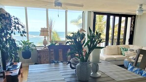 Een kamer met een houten tafel, een bank en uitzicht op zee.