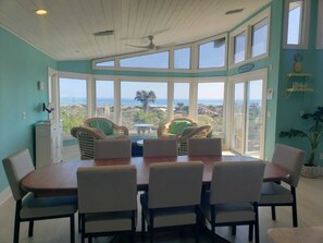 A dining area with a view of the ocean, featuring wicker chairs and a wooden table. - Rising Sun - Vacation Bliss! Ocean Front, Large Decks, & Private Beach Access (St. Augustine)