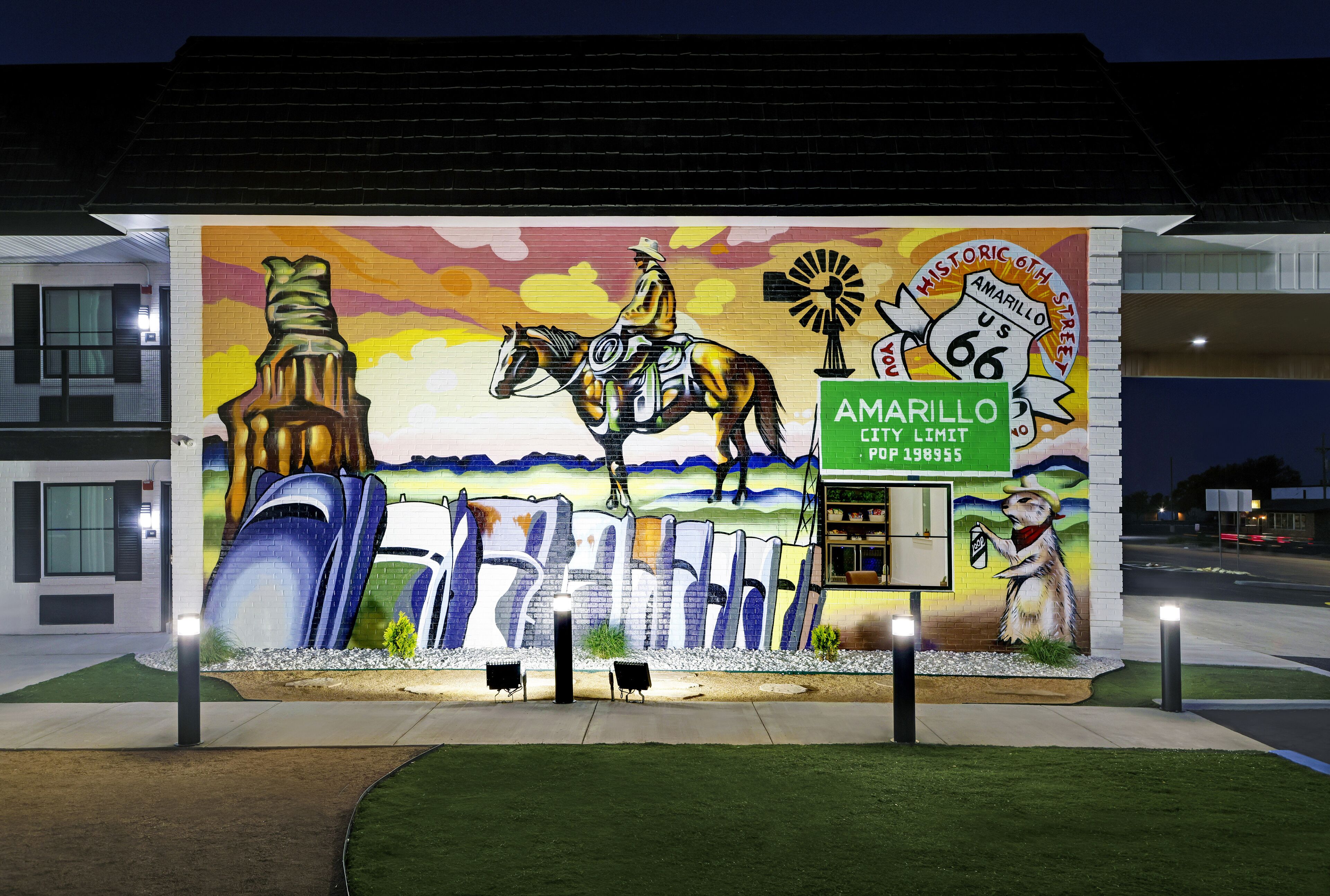 En mural med en cowboy på hest, en vindmølle og et skilt for Amarillo City Limit.