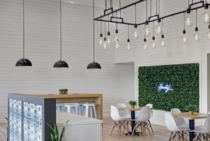 A modern dining area with pendant lights, a neon sign, and a green wall.