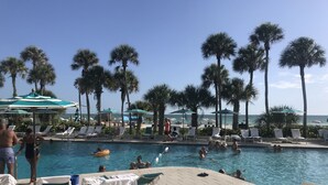 A pool area with lounge chairs and umbrellas, surrounded by palm trees. - Hemingway Inspired Villa (Sarasota)