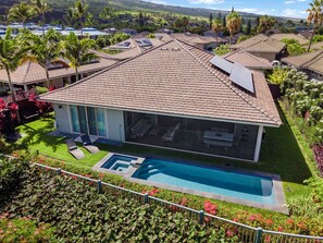 Una casa moderna con piscina, rodeada de exuberante vegetación y palmeras.