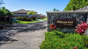 A residential area with a stone wall sign reading "HOLUA KAI AT KE AUHOU". - Holua Kai #27: Luxury Oceanfront Villa w/Private and Resort Pools & Spas (Kailua Kona)