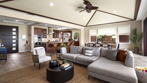 A spacious living room with a large sectional sofa, a coffee table, and a ceiling fan. - Holua Kai #27: Luxury Oceanfront Villa w/Private and Resort Pools & Spas (Kailua Kona)