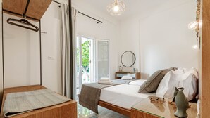 A modern bedroom with a bed, bedside table, and a mirror. - Villa Sun Sole (Corfu)