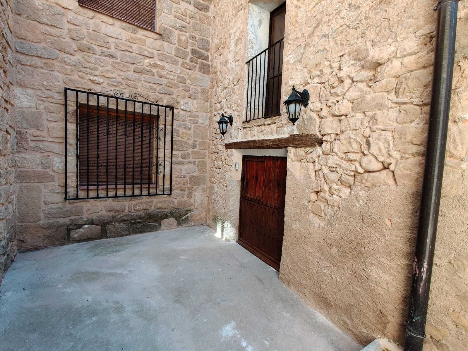 A narrow alley with stone walls, a wooden door, and a metal gate.