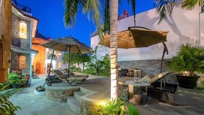 An outdoor patio area with lounge chairs, umbrellas, and a small table.
