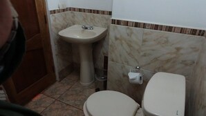 A bathroom with a sink, toilet, and a mirror. - Qorikilla Hostal (Cusco)