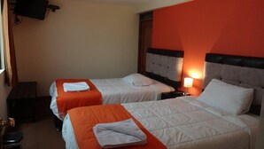 A hotel room with two beds, each with an orange bedspread and white pillows. There is a television mounted on the wall and a nightstand with a lamp. - Qorikilla Hostal (Cusco)