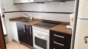 A compact kitchen with a stove, oven, sink, and a coffee maker. - Oropesa Ciudad de Vacaciones 3000 (Oropesa del Mar)