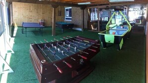 A room with a foosball table, a pool table, and a ping pong table. - Gala (Noja)